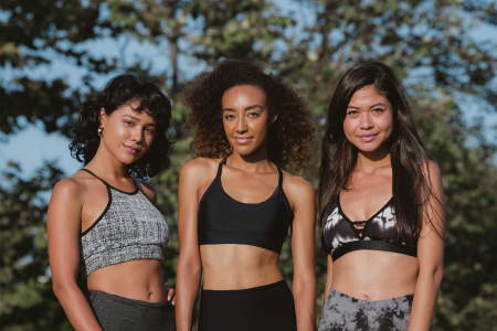 three fit healthy young women of color wearing leggings and sports bras in nature