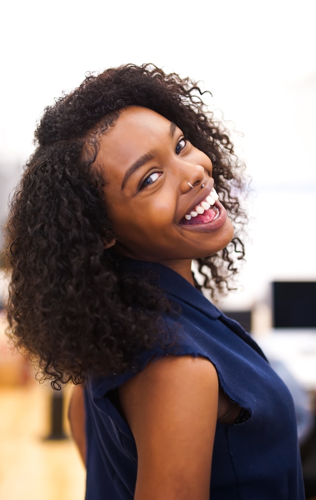 smiling black woman wearing a blue cut-off shirt
