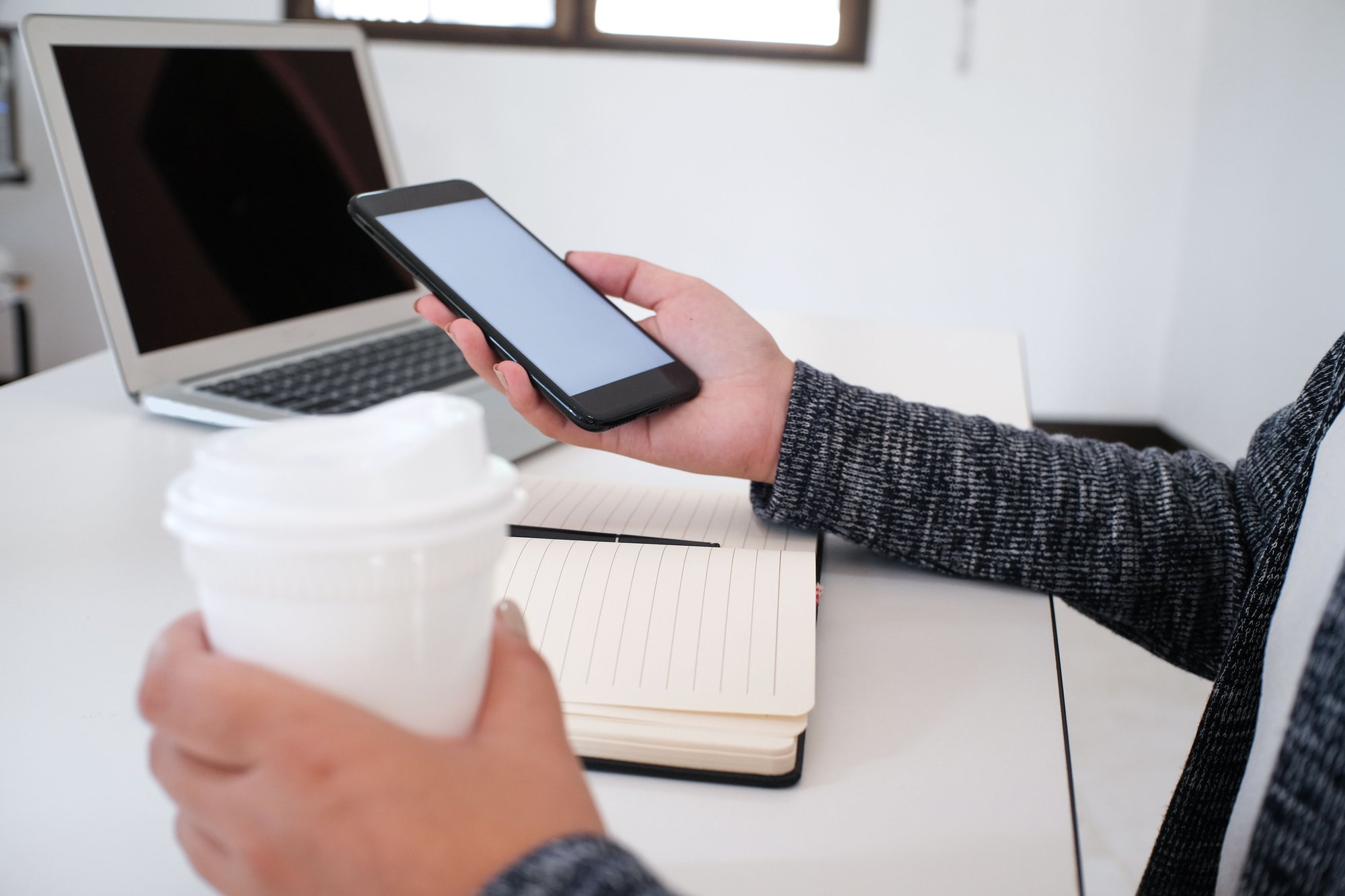 man working at his home office desk checking his phone from his coach