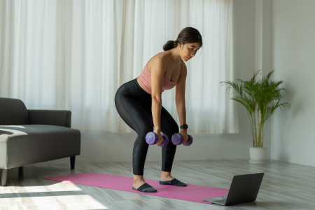 latin woman in activewear doing exercises with dumbbells at her home