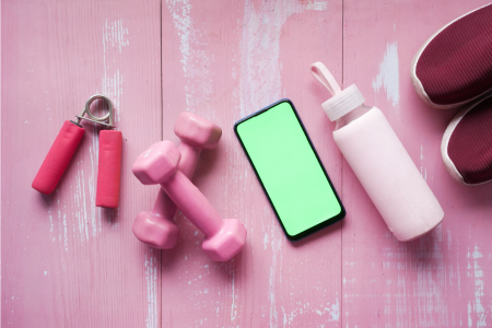 pink dumbbells, grip strength, mobile phone, and pink water container all on pink hardwood floor