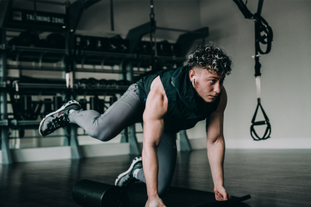 young athletic man doing leg exercises on a yoga mat in the gym