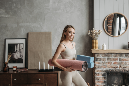 healthy fit woman holding her yoga mat and blocks after a great yoga session at her home